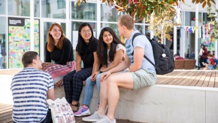 Group of five students sitting outdoors talking