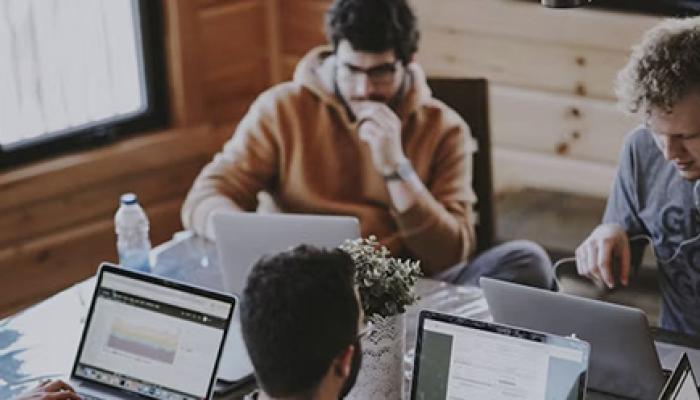 4 people watching on their laptops in a room